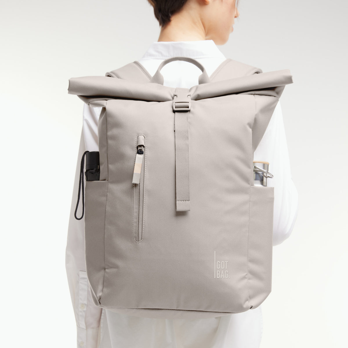 ROLLTOP EASY Rucksack in clam (helles, warmes Grau) von einer Frau als Rucksack auf dem Rücken getragen.