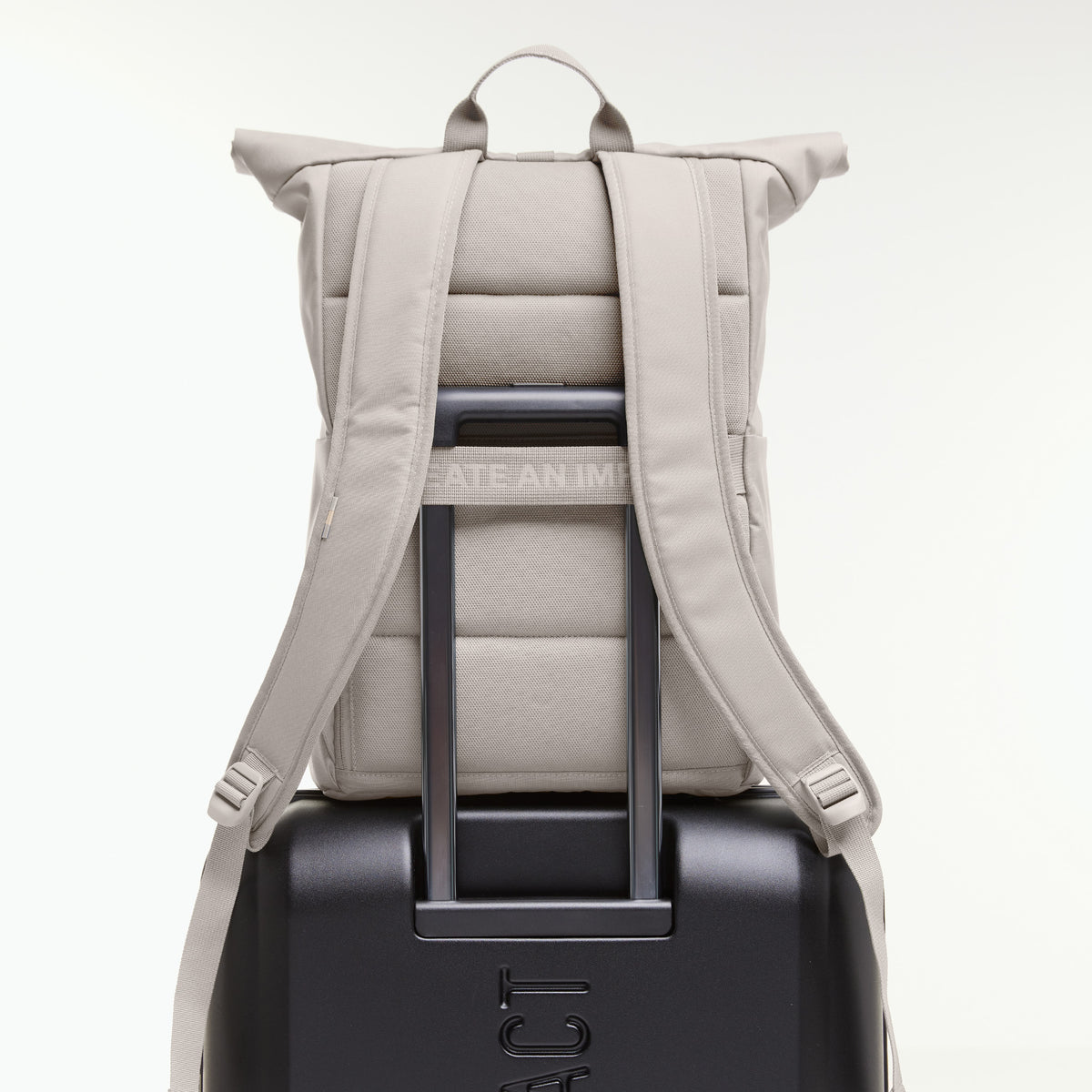 ROLLTOP EASY Rucksack in clam (helles, warmes Grau), von hinten auf einem Koffer.