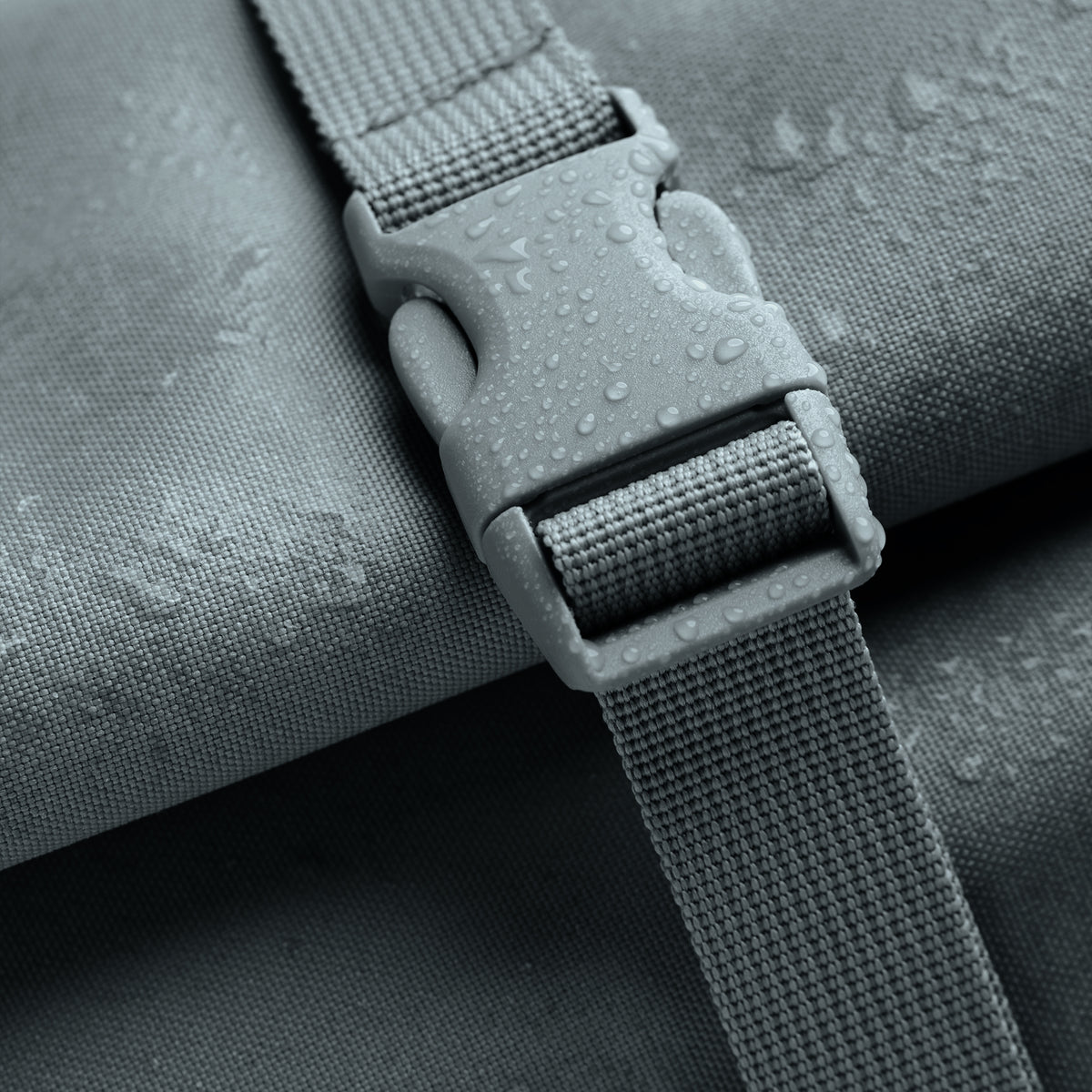 ROLLTOP LITE Rucksack in basalt (graues Eisblau) als Detailaufnahme mit Wassertropfen auf dem Stoff.
