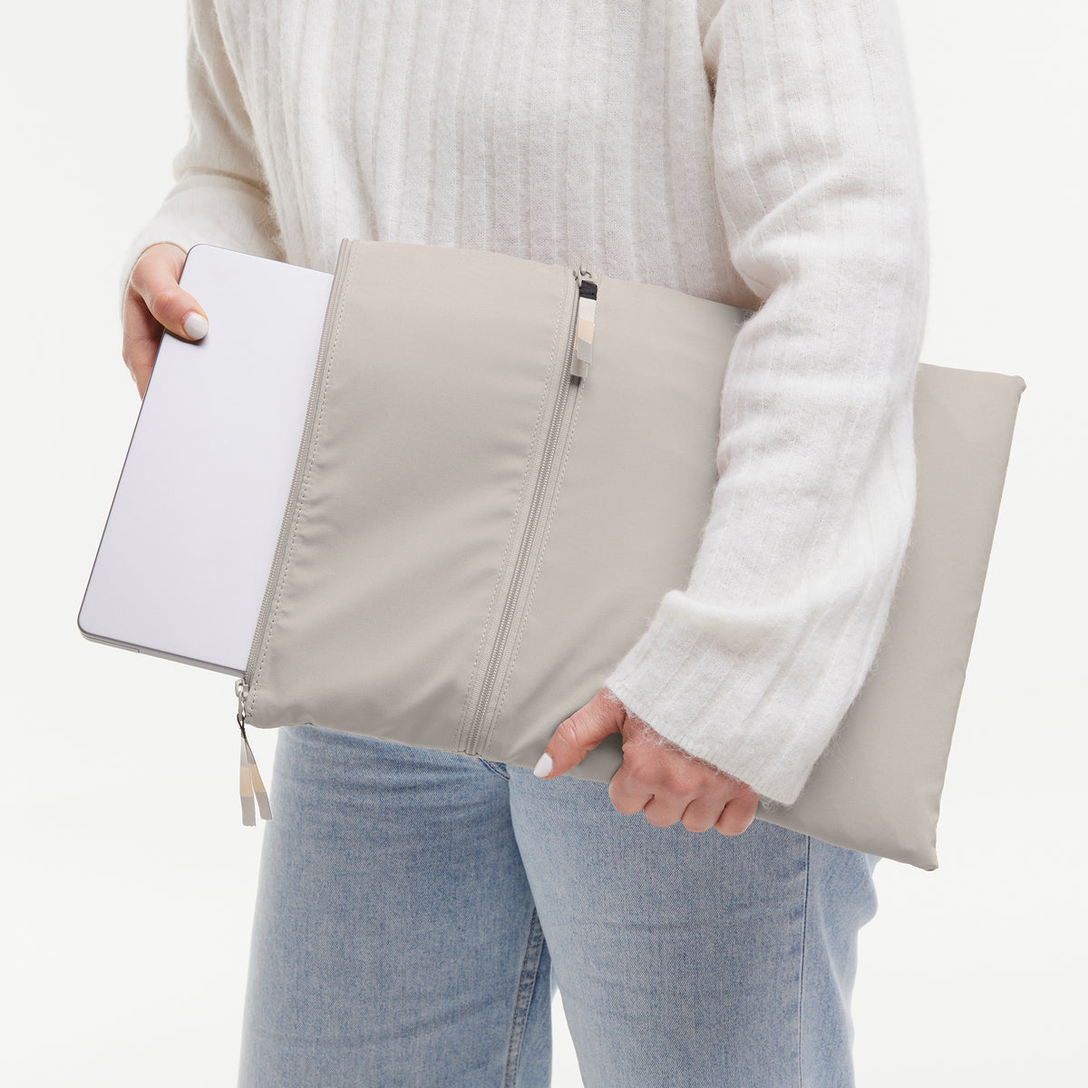 ROLLTOP LITE 2.0 MONOCHROME EDITION Accessoires in clam (helles, warmes Grau) von einer Frau, die einen Laptop in die Hülle schiebt.