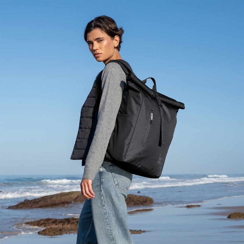 ROLLTOP EASY Monochrome Edition Rucksack in black (Schwarz) von einer Frau als Rucksack auf dem Rücken getragen.