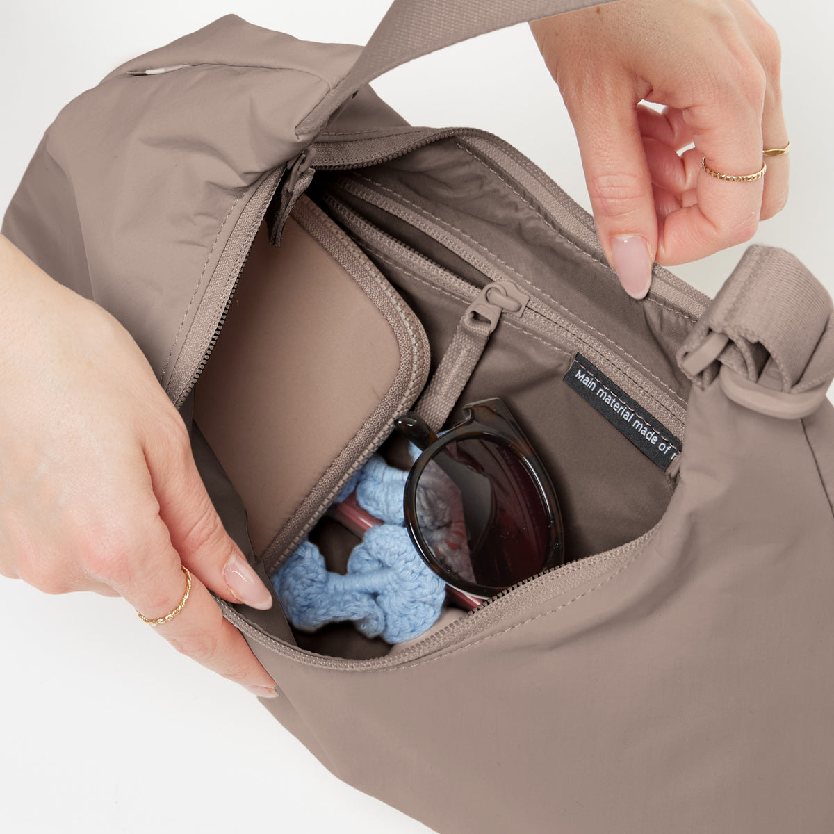 Innenansicht der T SHAPE BAG MINI Tasche in oyster (klassisches Taupe-Braun), von Händen einer Frau geöffnet.