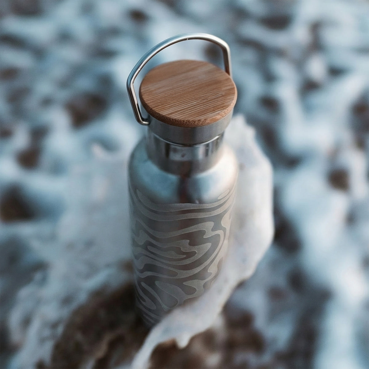 BOTTLE Accessoires mit eingraviertem Muster, umgeben von weißem Schaum. Detailansicht.