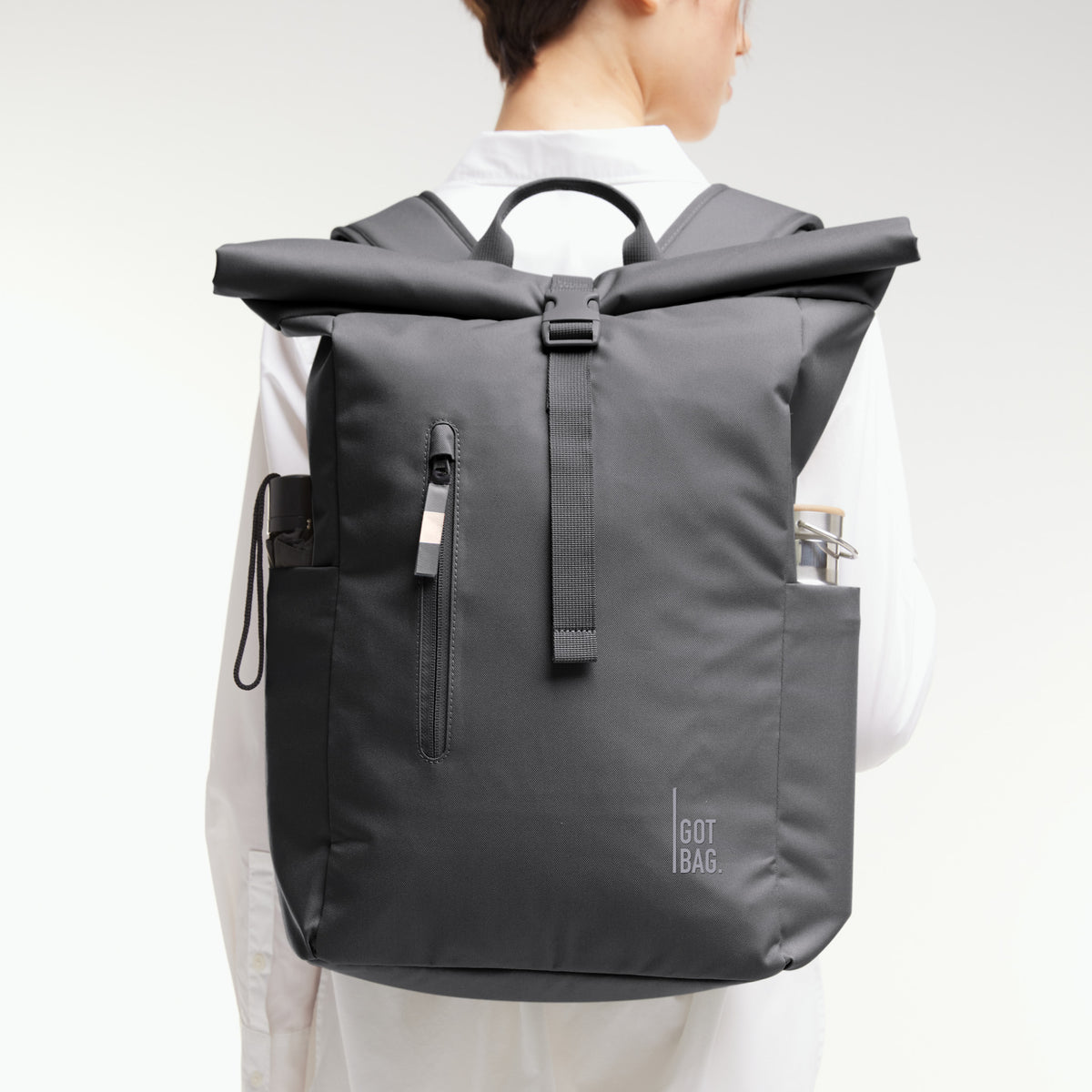 ROLLTOP EASY Rucksack in shark (Dunkelgrau) von einer Frau auf dem Rücken getragen, mit seitlichen Fächern.