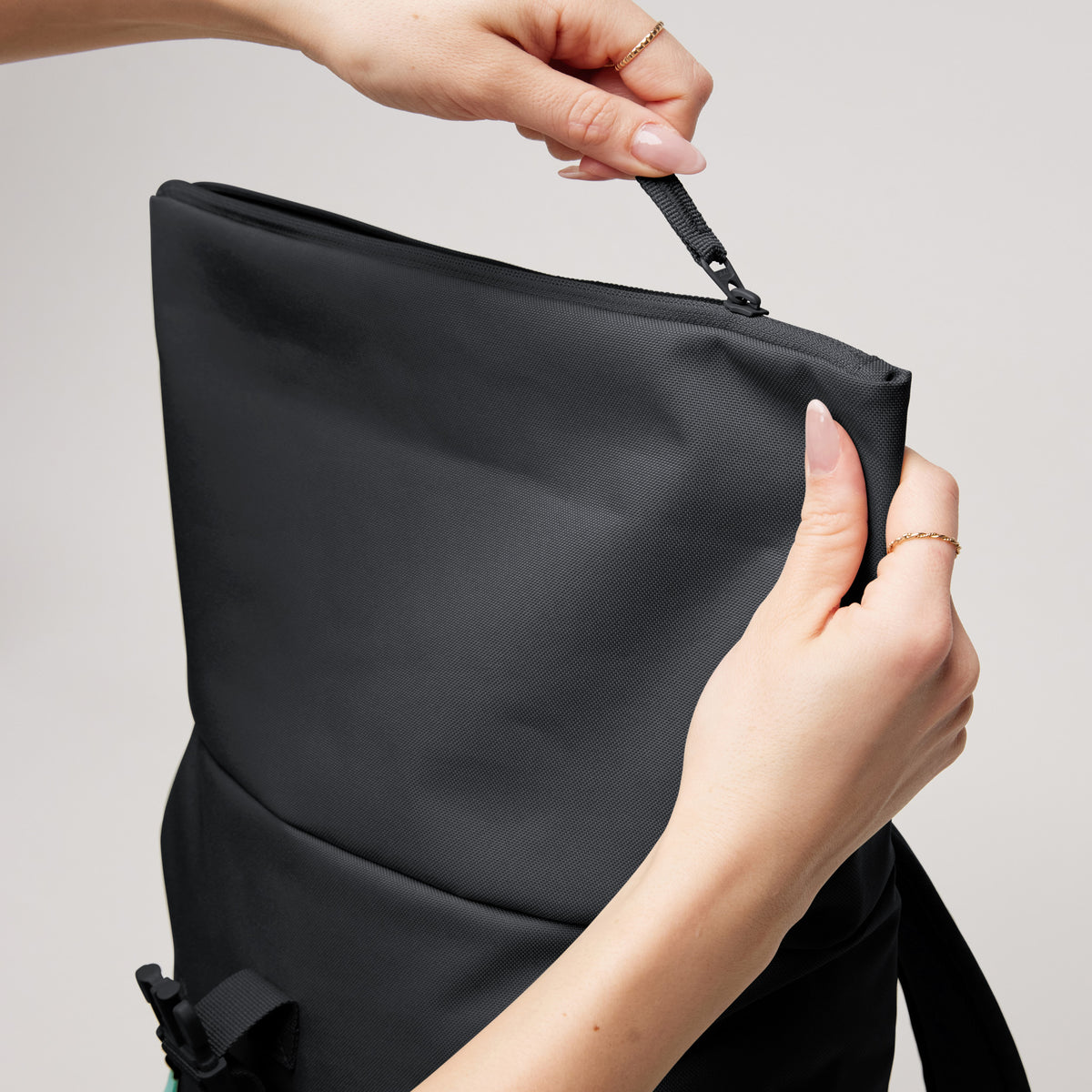 ROLLTOP EASY SMALL Rucksack in einer Detailaufnahme, Hände einer Frau bedienen den Reißverschluss.