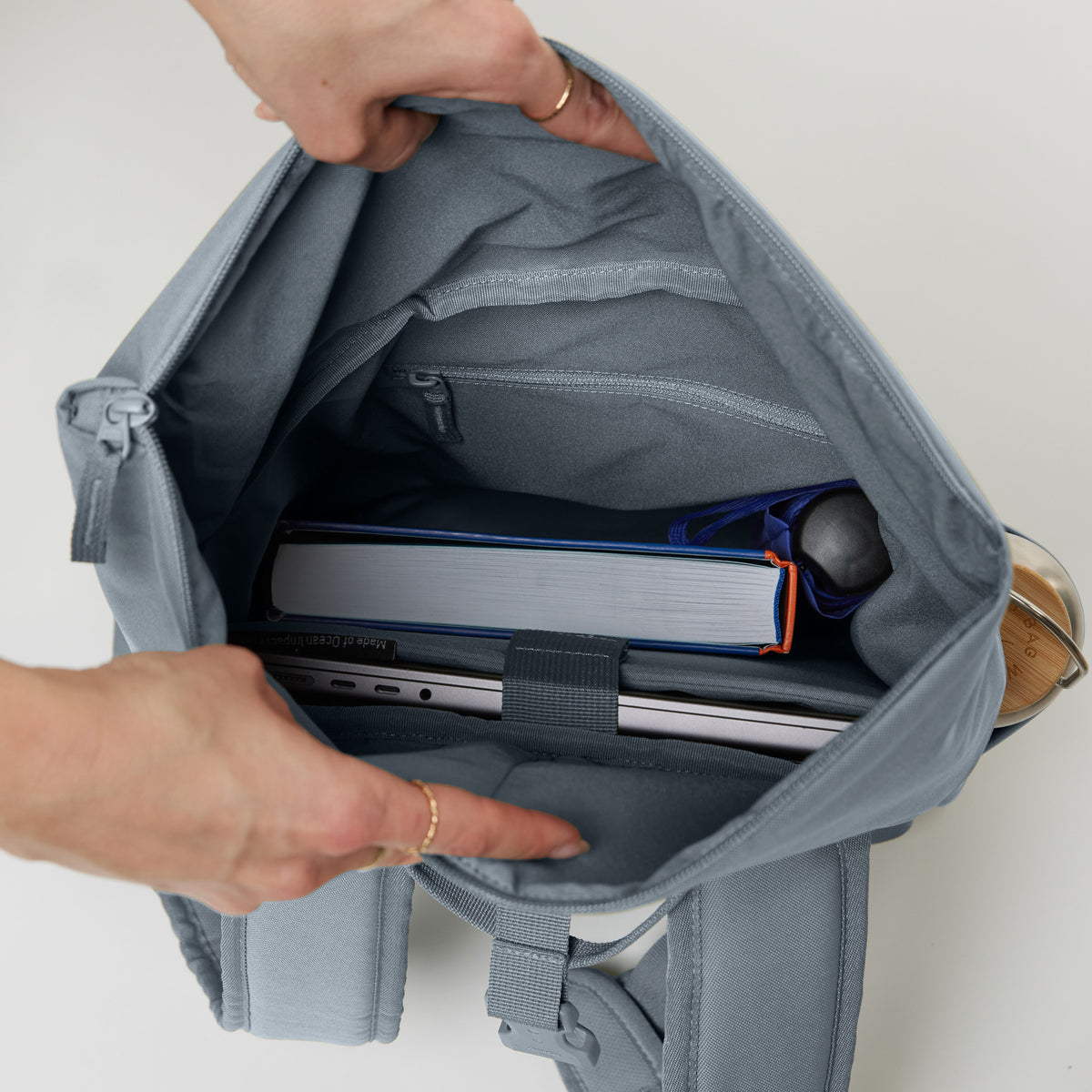 ROLLTOP EASY SMALL Rucksack in marlin (grau-blau), Innenansicht mit Laptop und Buch.