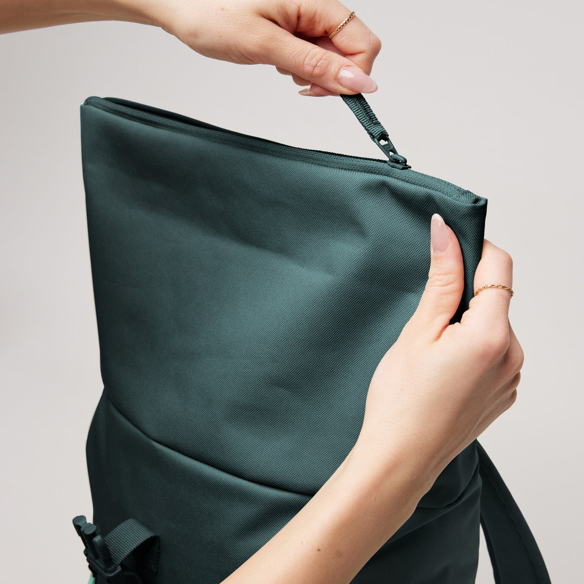 ROLLTOP EASY SMALL Rucksack in sea teal (kühles Türkisgrün) von einer Frau mit Reißverschluss geöffnet.