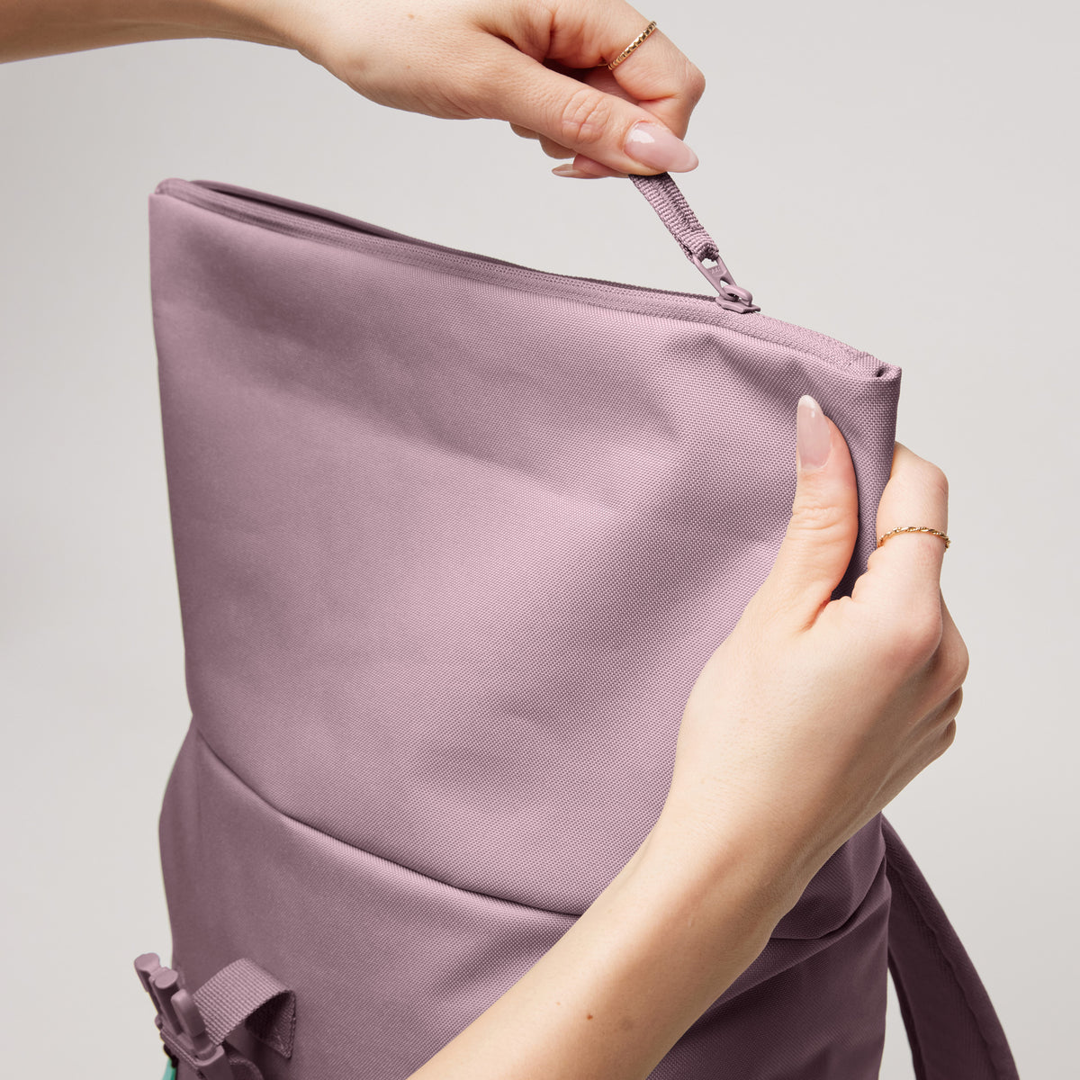 ROLLTOP EASY SMALL Rucksack in calamary (Altrosa), Hände einer Frau öffnen den Reißverschluss.
