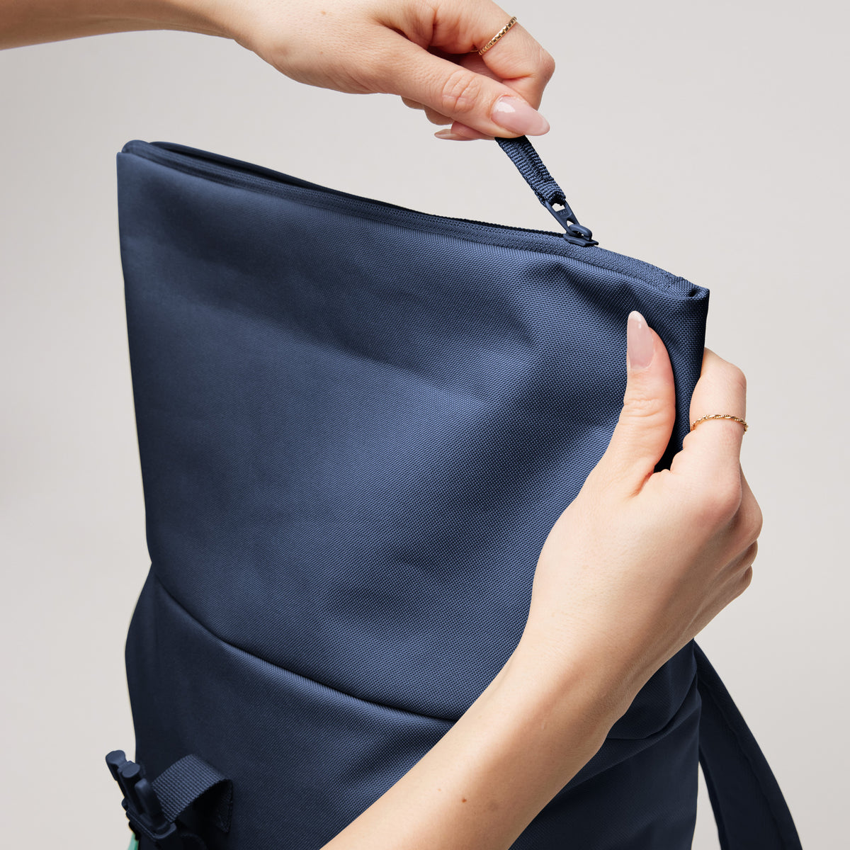 ROLLTOP EASY SMALL Rucksack in deep ocean (dunkles Marineblau) von einer Frau am Reißverschluss geöffnet.