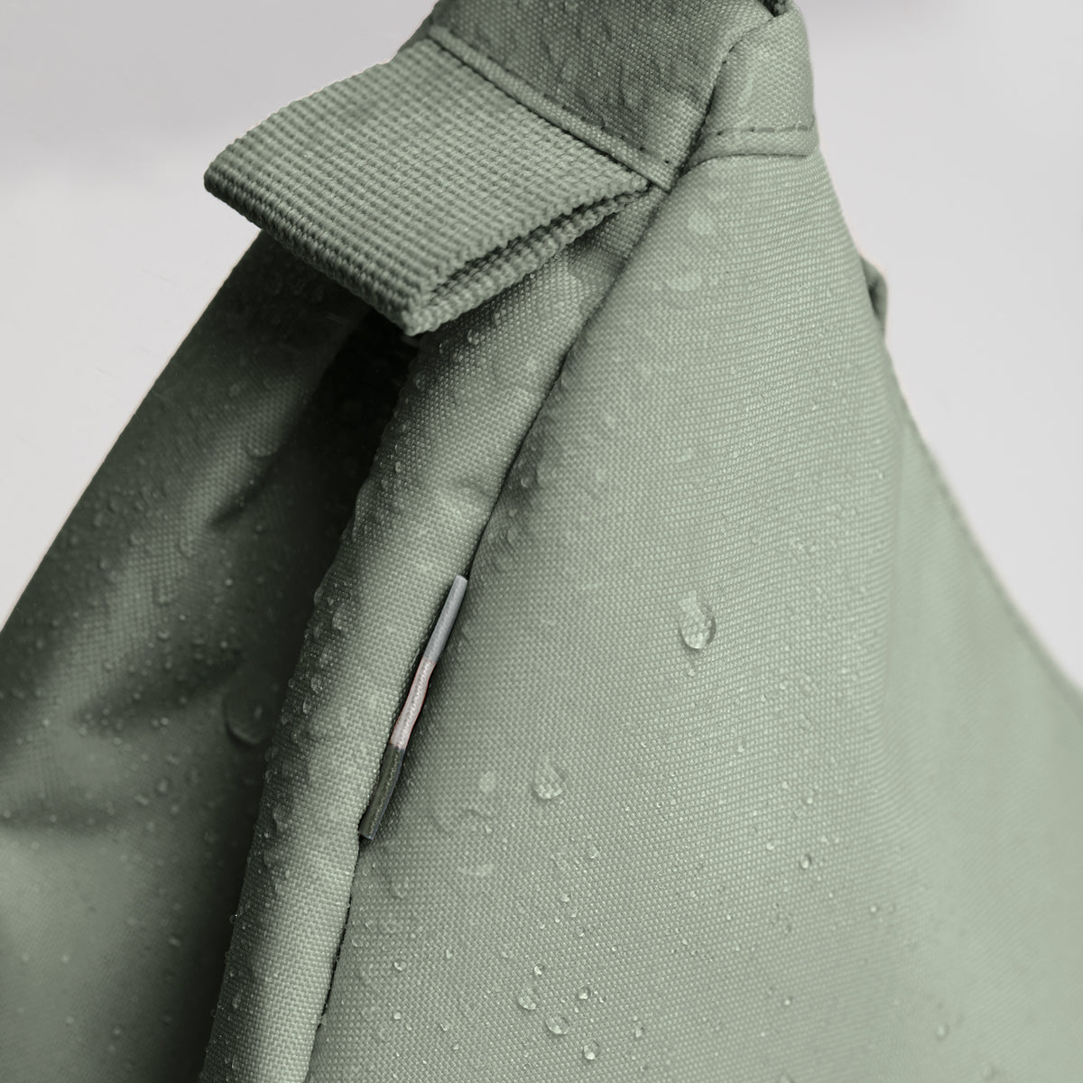 MOON BAG SMALL Tasche in bass (Salbeigrün), wasserabweisende Detailaufnahme mit Wassertropfen.