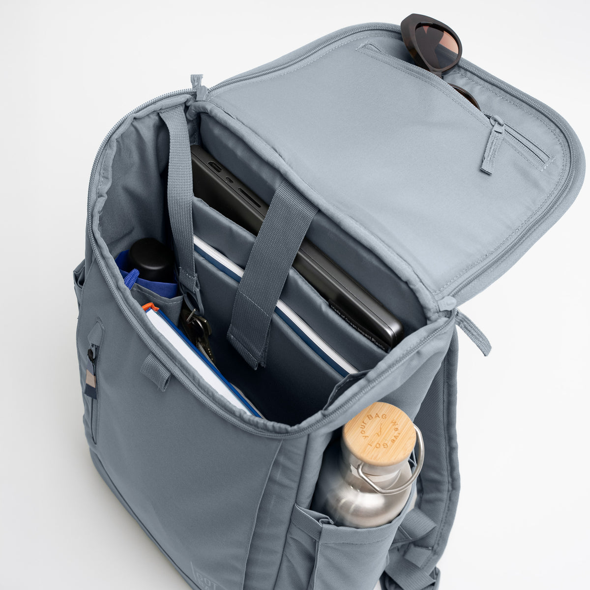 SERENE PACK Rucksack in marlin (grau-blau) geöffnet und mit diversen Gegenständen gefüllt.