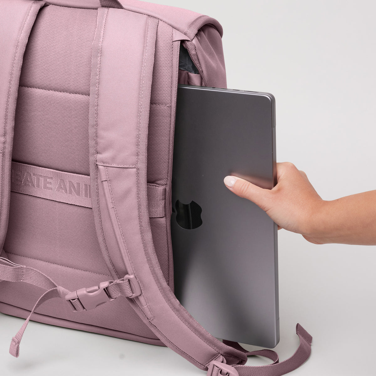 SERENE PACK Rucksack in calamary (Altrosa) von einer Frau, die ein Laptop einsteckt.