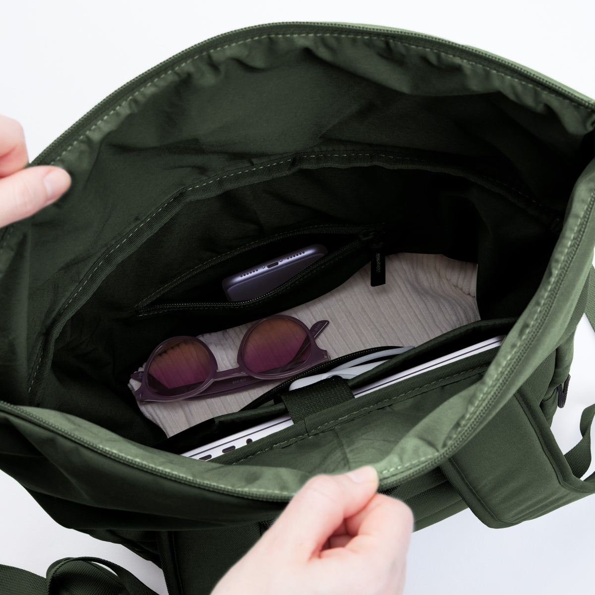 ROLLTOP EASY Rucksack in algae (Dunkelgrün mit Graustich) Detailaufnahme des Innenraums mit Handy, Sonnenbrille und Laptop.