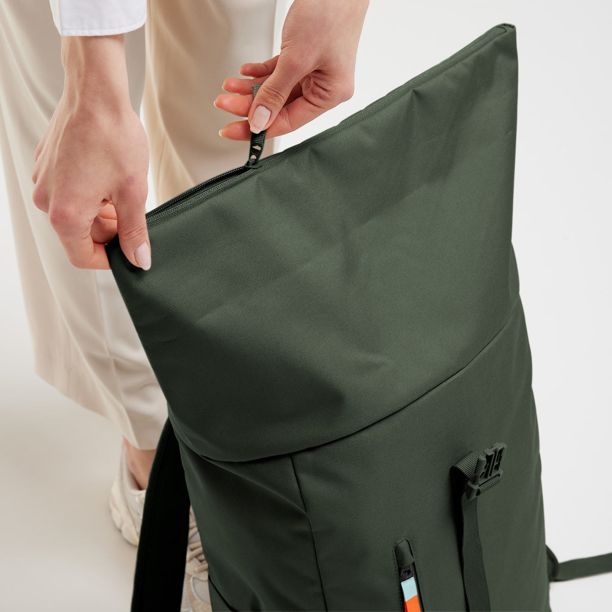 ROLLTOP EASY Rucksack in algae (Dunkelgrün mit Graustich), von einer Frau beim Öffnen der oberen Reißverschlussöffnung.