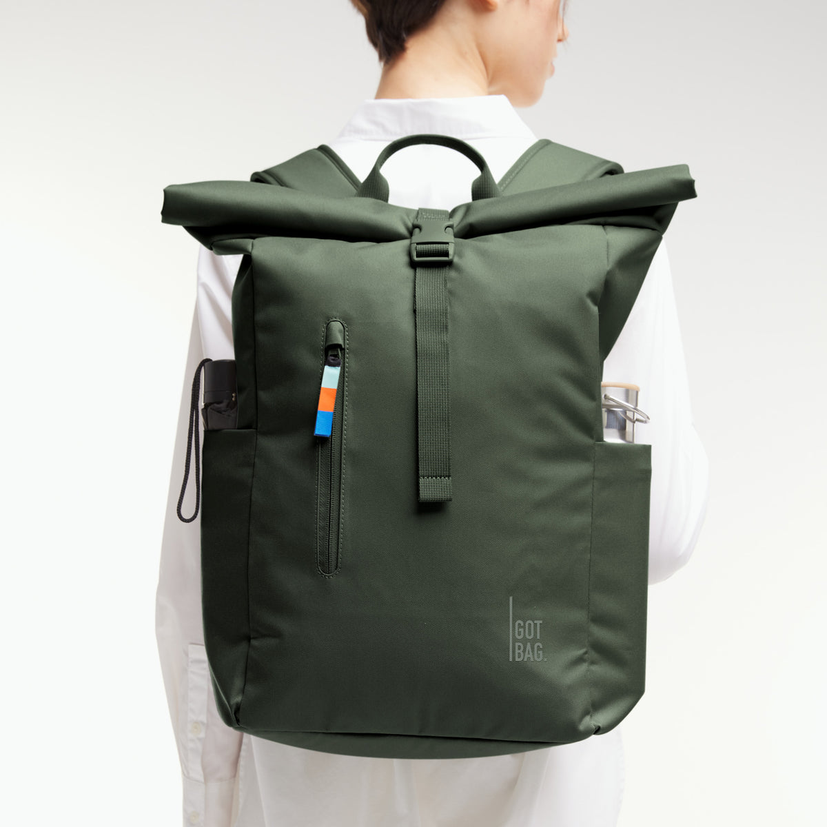 ROLLTOP EASY Rucksack in algae (Dunkelgrün mit Graustich) von einer Frau auf dem Rücken getragen, mit gefüllten Seitentaschen.