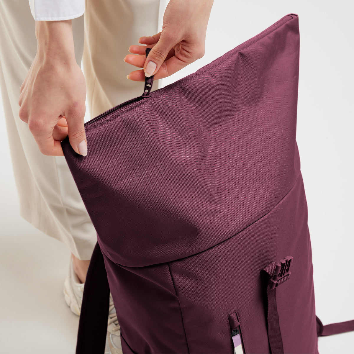 ROLLTOP EASY Rucksack in kraken (Weinrot) von einer Frau am Reißverschluss geöffnet.