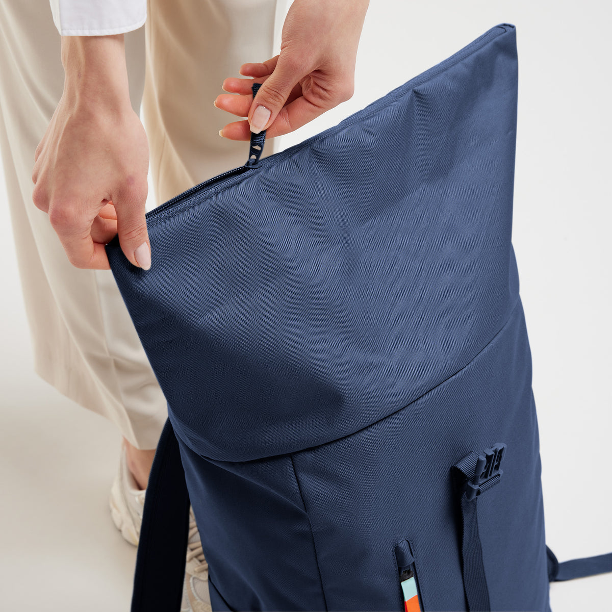 ROLLTOP EASY Rucksack in deep ocean (dunkles Marineblau), wird von einer Frau am Reißverschluss geöffnet.