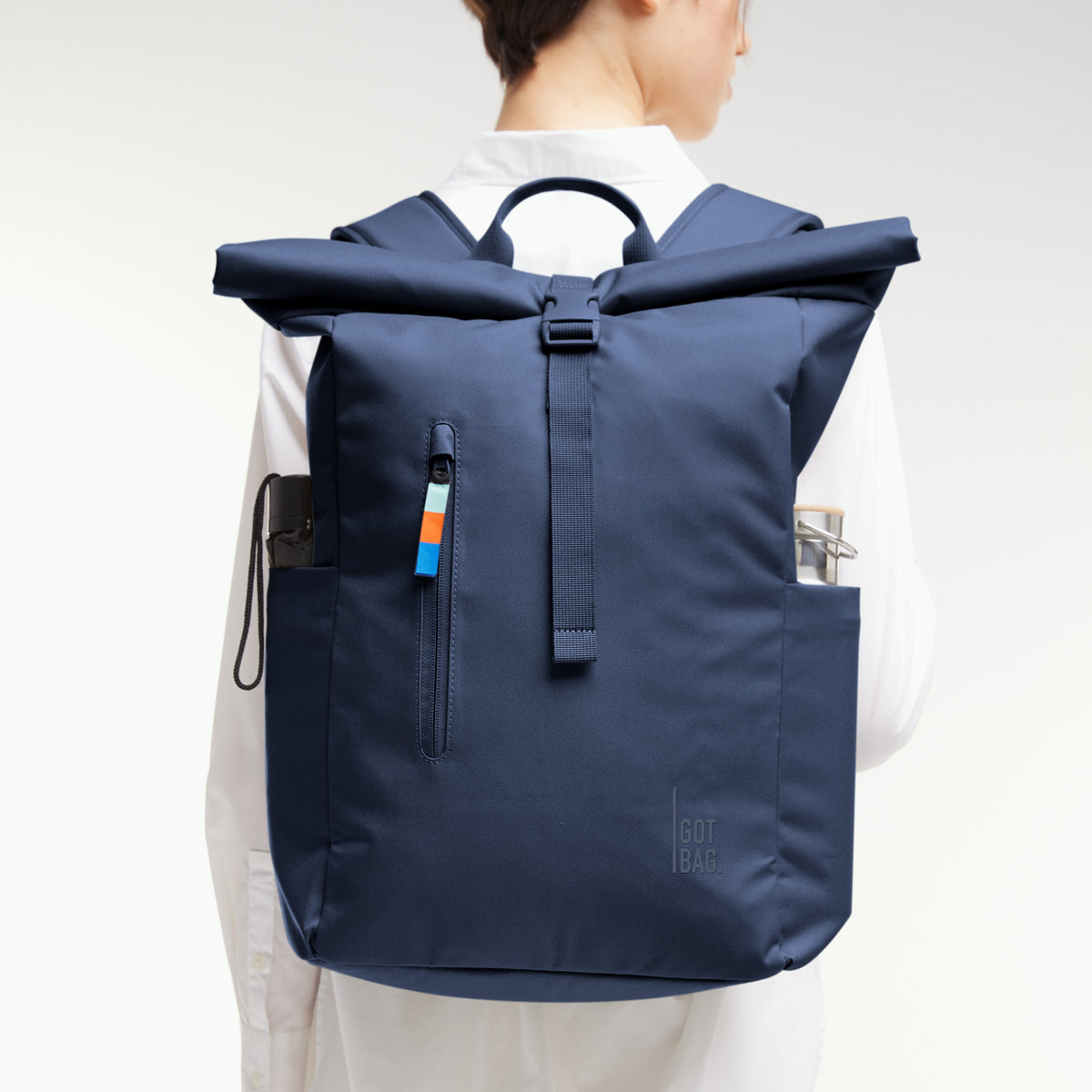 ROLLTOP EASY Rucksack in deep ocean (dunkles Marineblau) von einer Frau auf dem Rücken getragen.