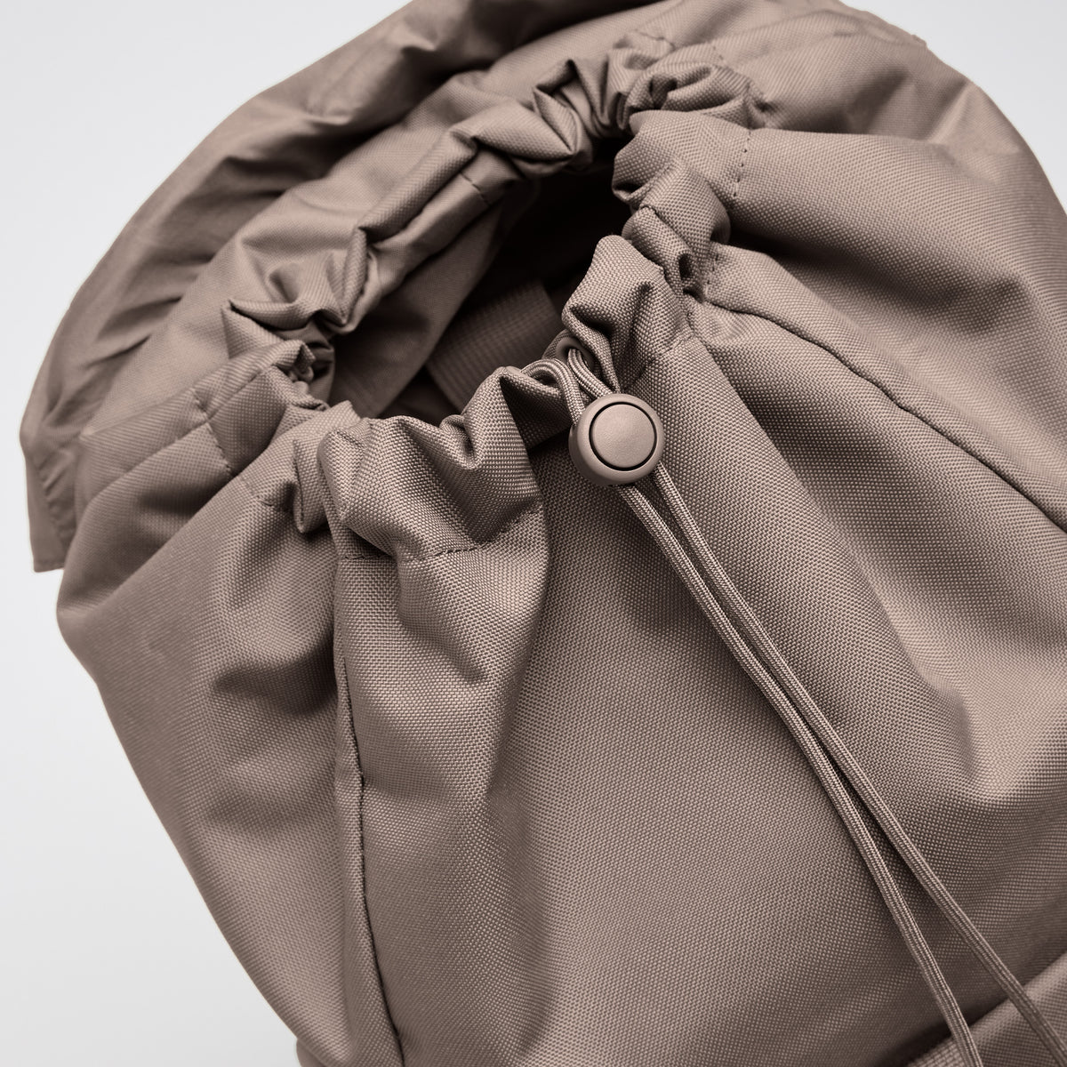 FLAP PACK LARGE Rucksack in oyster (klassisches Taupe-Braun), Detailaufnahme des Kordelzugverschlusses.