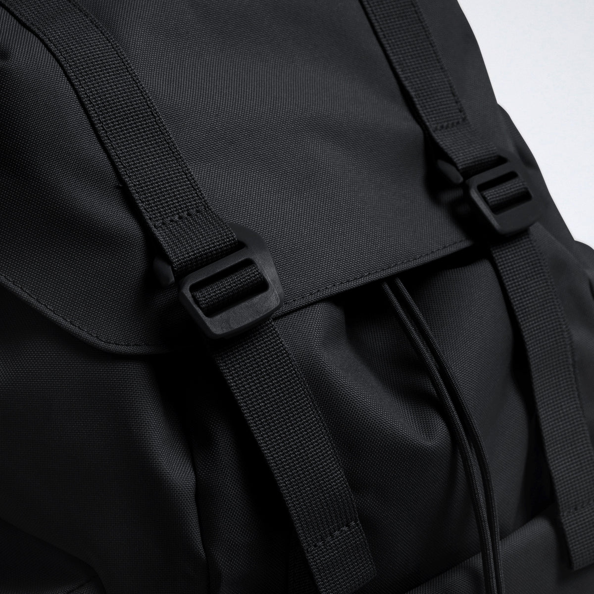 FLAP PACK LARGE Rucksack in black (Schwarz). Detailaufnahme der Schnallen und des Kordelzugs am Verschluss.