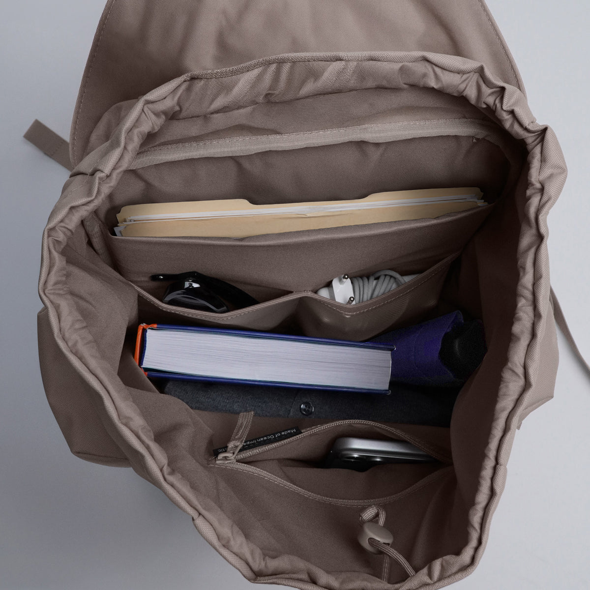 FLAP PACK LARGE Rucksack in oyster (klassisches Taupe-Braun) Innenansicht mit diversen persönlichen Gegenständen.