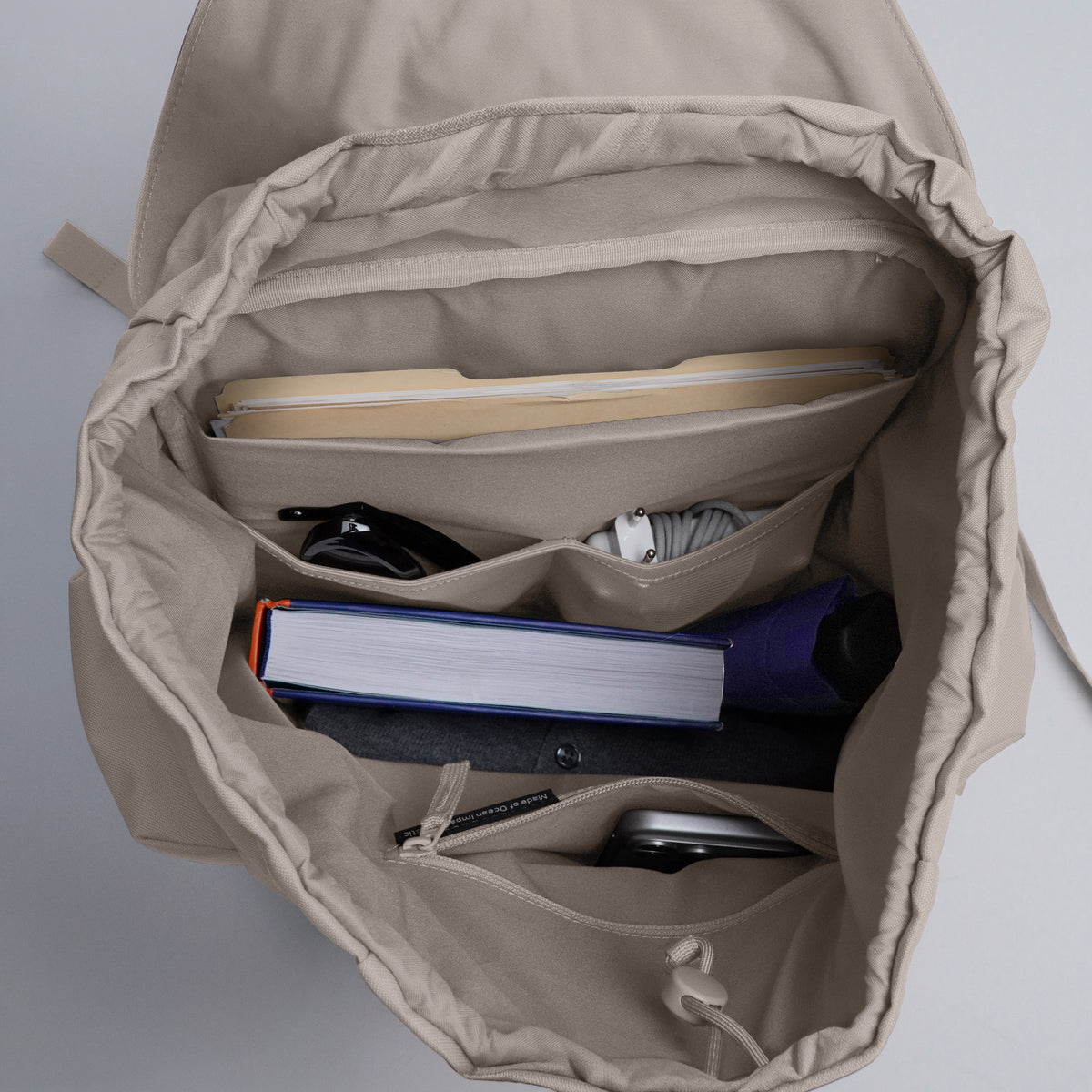 FLAP PACK LARGE Rucksack in scallop (helles Beige), Innenansicht mit verschiedenen Fächern und Gegenständen.