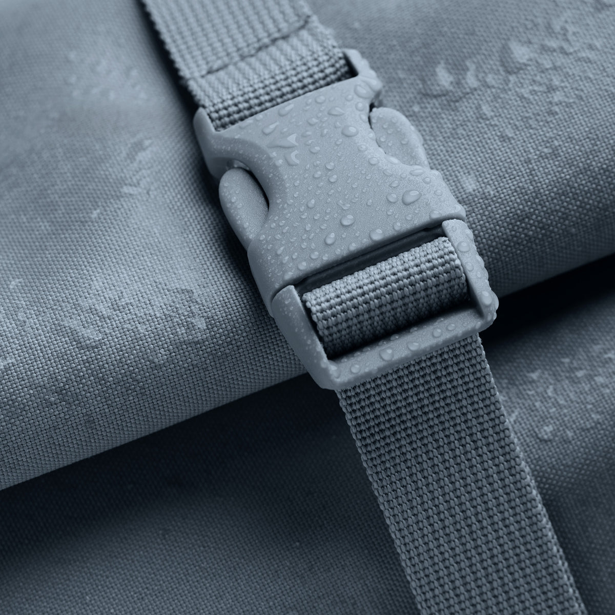 ROLLTOP Rucksack Monochrome Edition in marlin (grau-blau), Detailaufnahme der wasserabweisenden Oberfläche mit Wassertropfen.