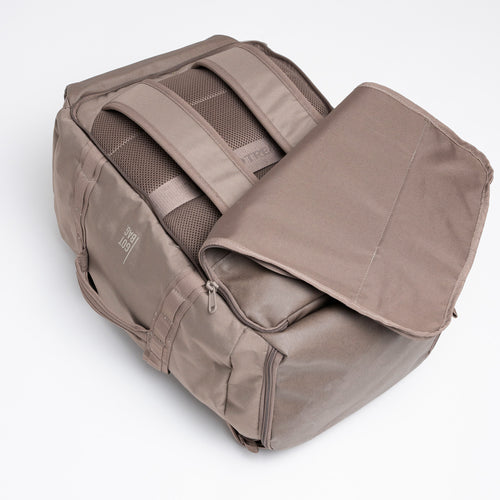 DUFFLE PACK Rucksack in oyster (klassisches Taupe-Braun) auf weißem Hintergrund, von oben geöffnet.