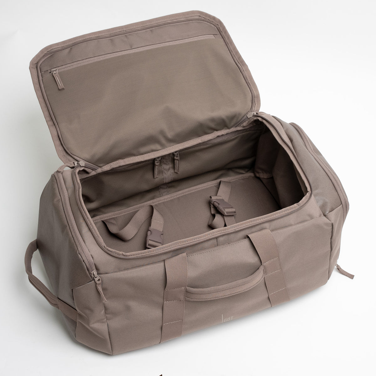 DUFFLE PACK Tasche in oyster (klassisches Taupe-Braun), offener Innenraum mit Fächern und Gurten.