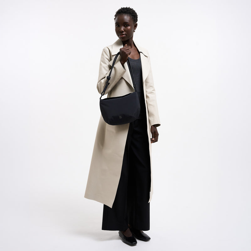 CLAM BAG Tasche in black (Schwarz) von einer Frau in der Hand gehalten.