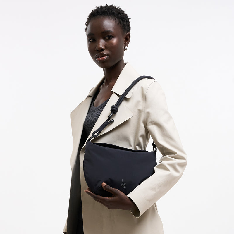 CLAM BAG Tasche in black (Schwarz) von einer Frau in der Hand gehalten.