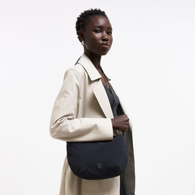 CLAM BAG Tasche in black (Schwarz) von einer Frau crossbody getragen.