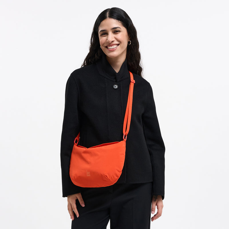 CLAM BAG Tasche in hot coral (knalliges Orange) von einer Frau crossbody getragen.