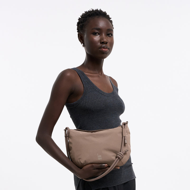 CLAM BAG bag in oyster (classic taupe-brown) held by a woman in her hand.