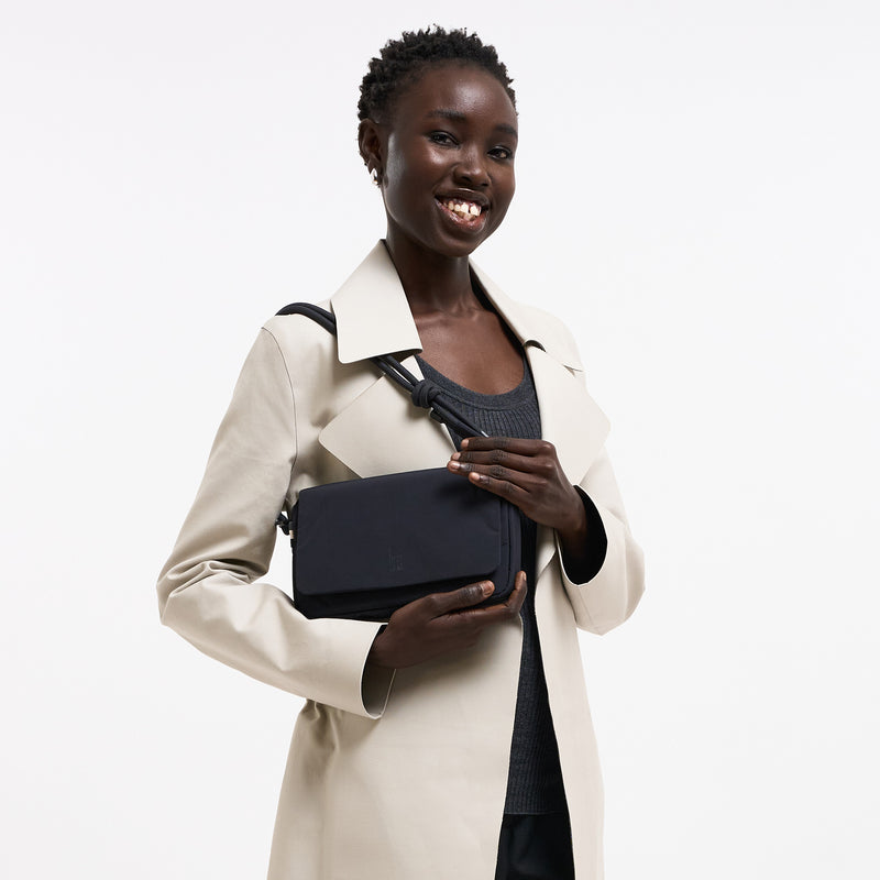 FACET BAG Tasche in black (Schwarz) von einer Frau crossbody getragen.