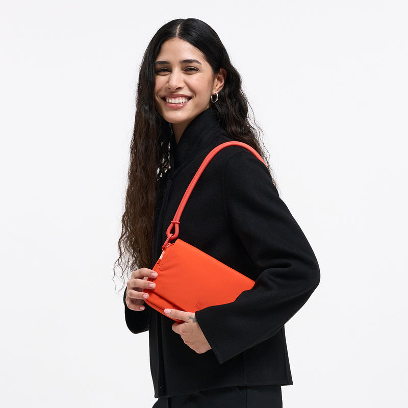 FACET BAG bag in hot coral (vibrant orange) carried by a woman.