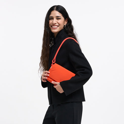 FACET BAG Tasche in hot coral (knalliges Orange) von einer Frau über der Schulter getragen.