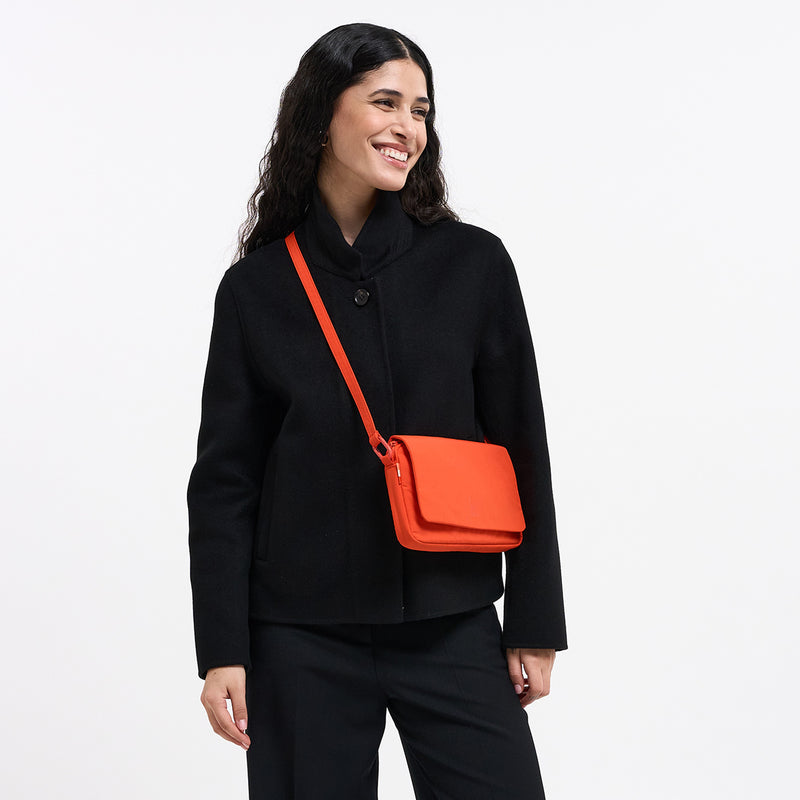 FACET BAG Tasche in hot coral (knalliges Orange) von einer Frau crossbody getragen.
