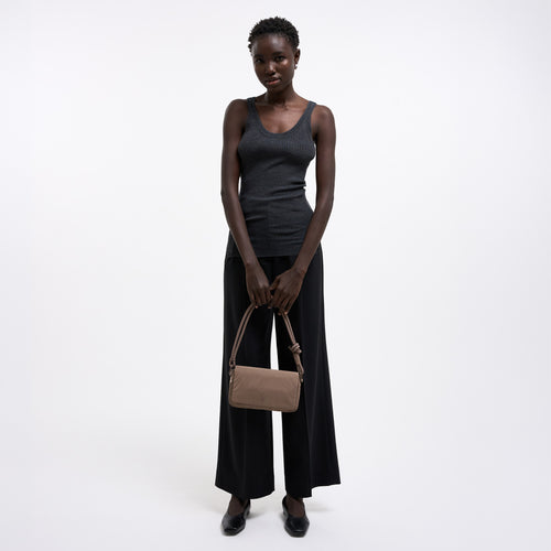 FACET BAG Tasche in oyster (klassisches Taupe-Braun) von einer Frau in der Hand gehalten.