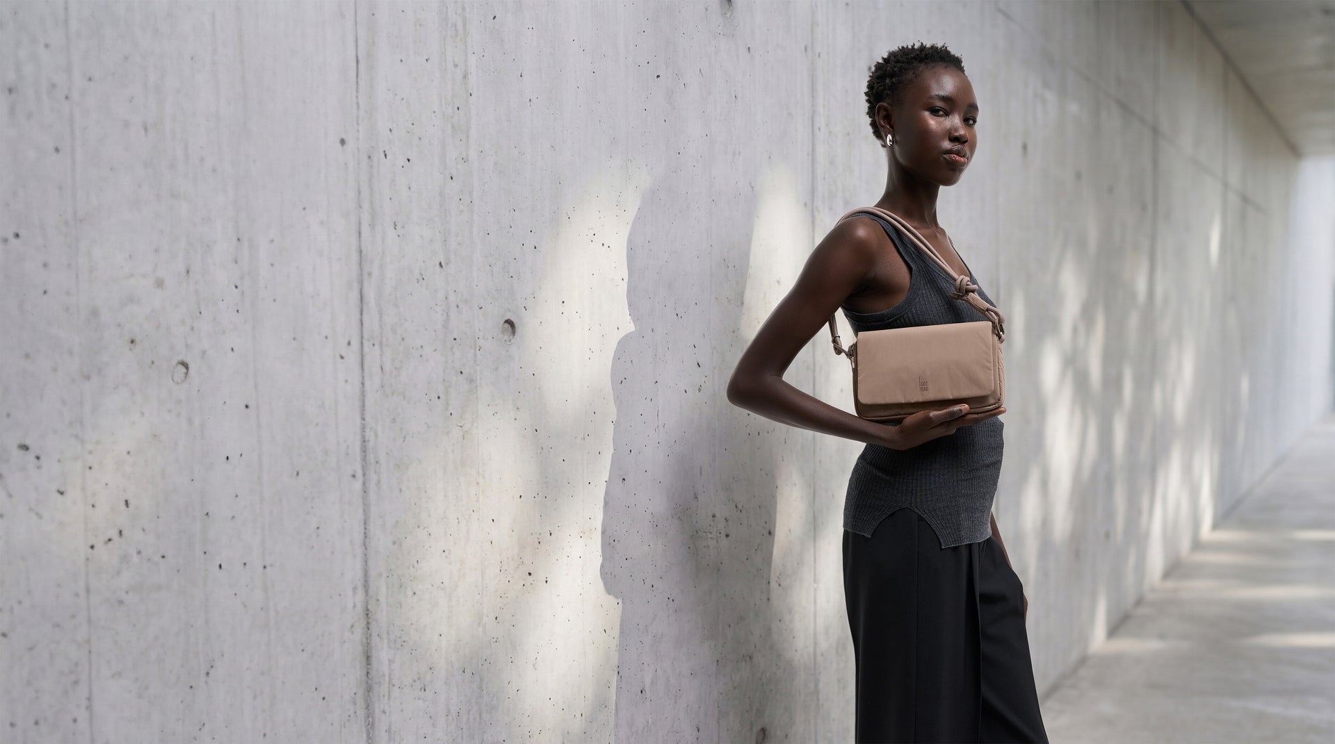 FACET BAG bag in oyster (classic taupe-brown) worn crossbody by a woman.