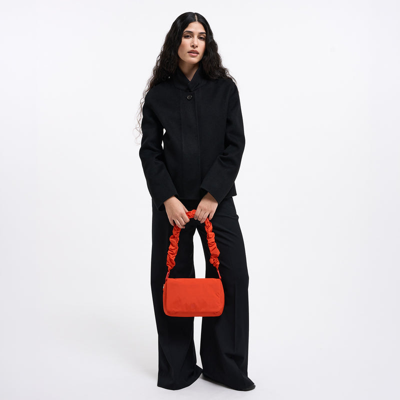 LUCID BAG Tasche in hot coral (knalliges Orange) von einer Frau in den Händen gehalten.