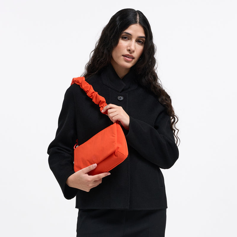 LUCID BAG Tasche in hot coral (knalliges Orange) von einer Frau über der Schulter getragen.