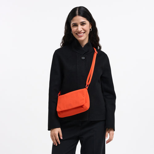 LUCID BAG Tasche in hot coral (knalliges Orange) von einer Frau crossbody getragen.