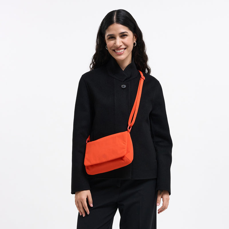 LUCID BAG Tasche in hot coral (knalliges Orange) von einer Frau crossbody getragen.