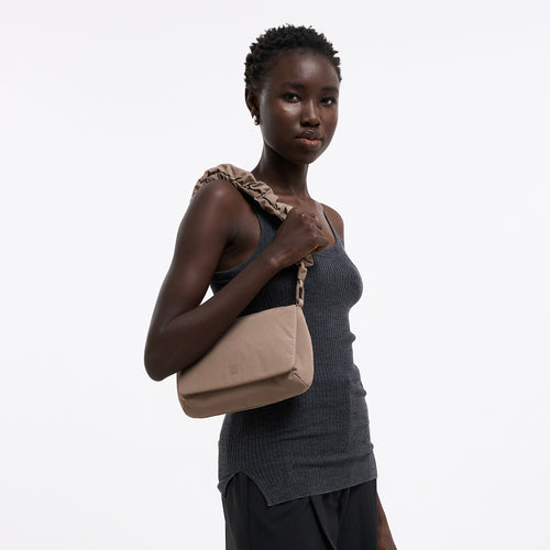 LUCID BAG Tasche in oyster (klassisches Taupe-Braun) von einer Frau über der Schulter getragen.