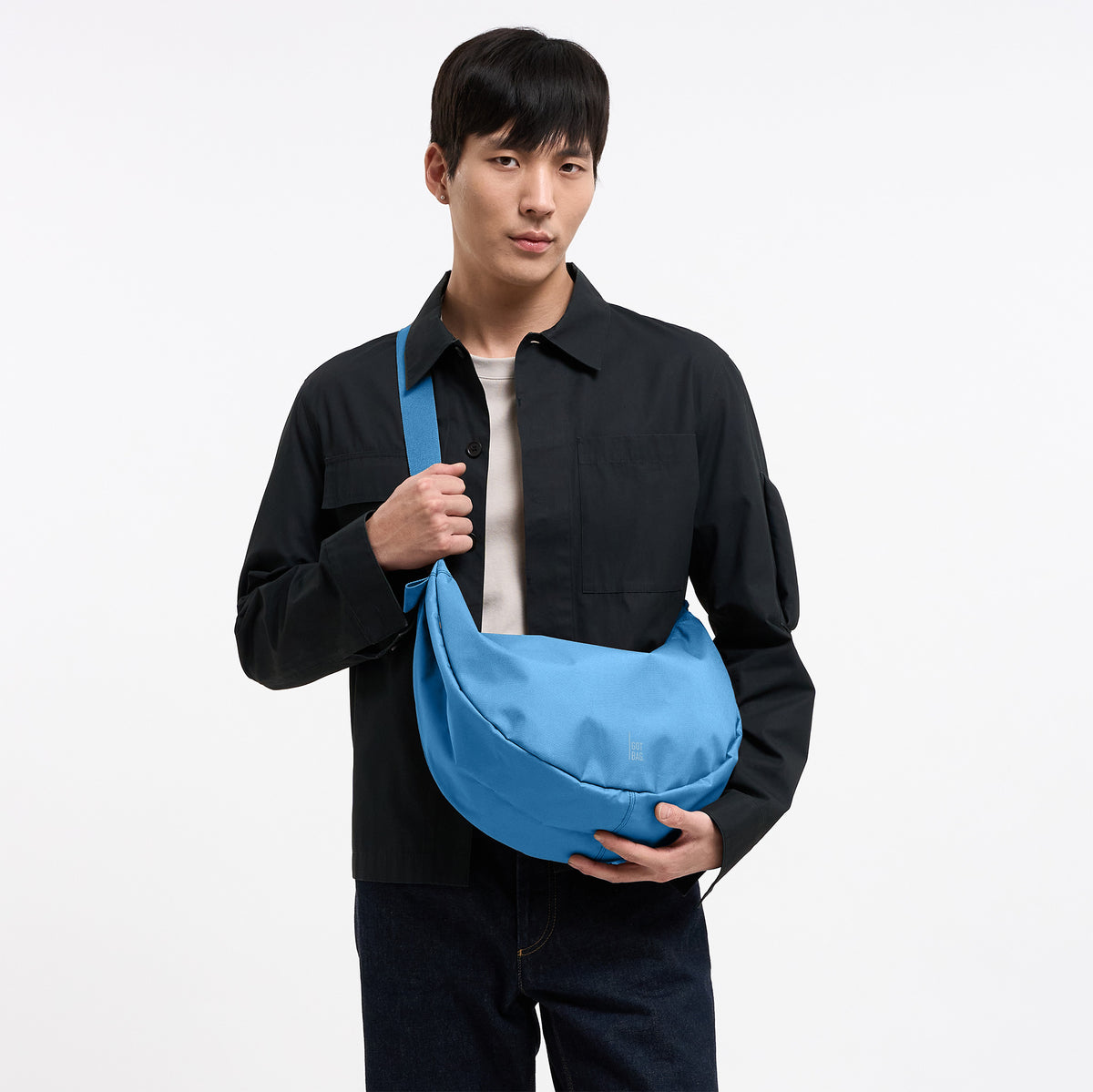 MOON BAG LARGE Tasche in aqua (leuchtendes Hellblau) von einem Mann crossbody getragen.