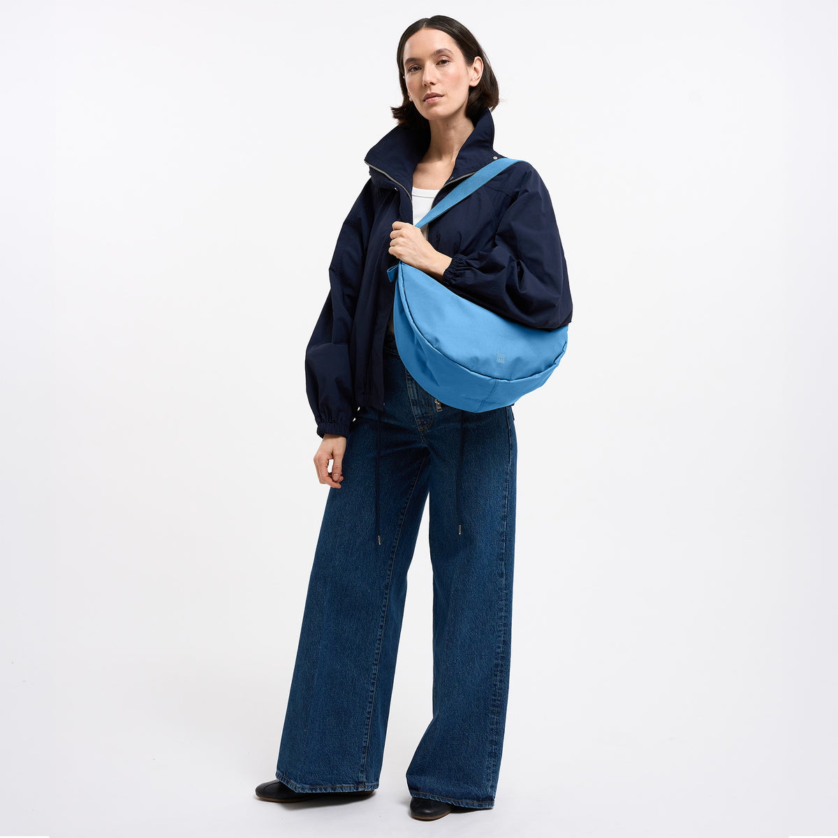 MOON BAG LARGE Tasche in aqua (leuchtendes Hellblau) von einer Frau crossbody getragen.