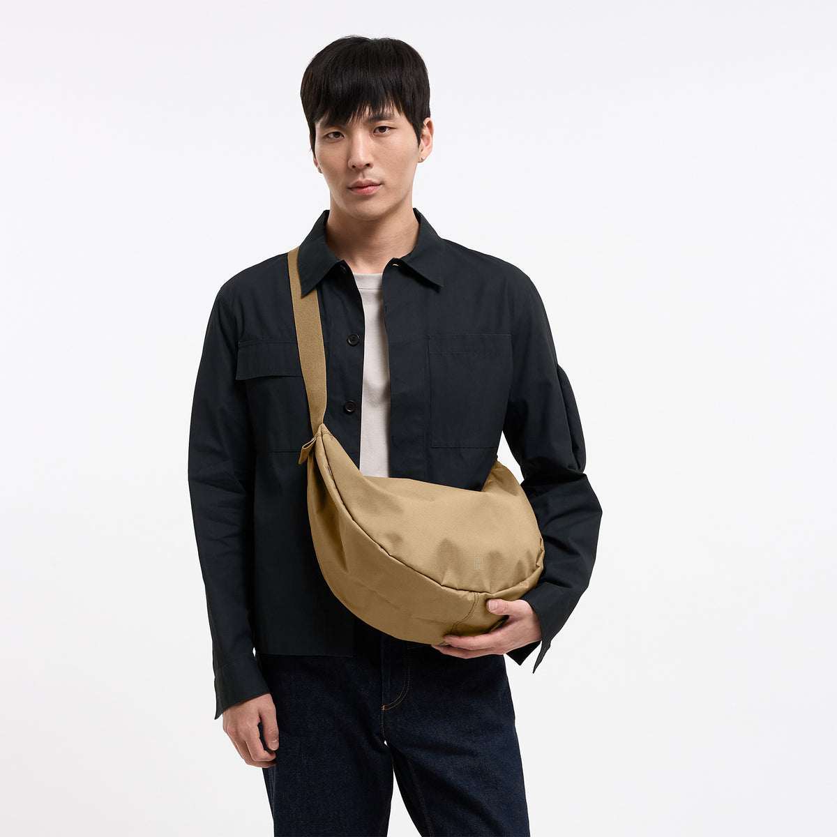 MOON BAG LARGE Tasche in sea moss (warmes Beige-Khaki) von einem Mann crossbody getragen.