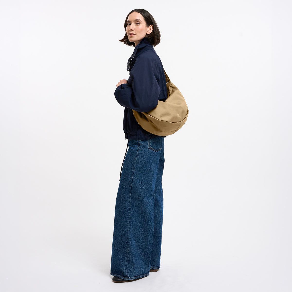 MOON BAG LARGE Tasche in sea moss (warmes Beige-Khaki) von einer Frau über der Schulter getragen.