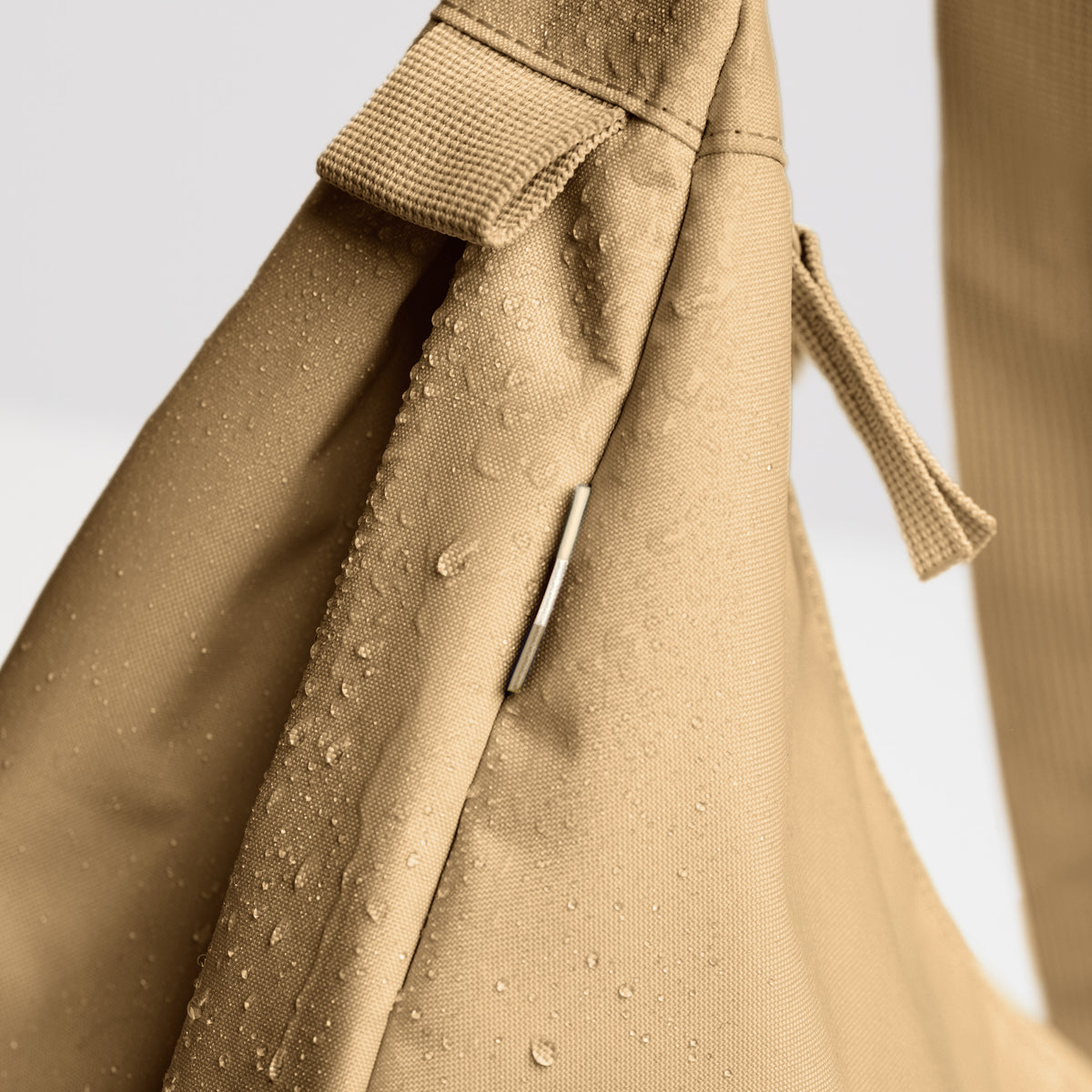MOON BAG LARGE Tasche in sea moss (warmes Beige-Khaki), Detailaufnahme mit Wassertropfen auf wasserabweisendem Stoff.